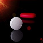 White round tablet with one red pill in background. Black background with reflection